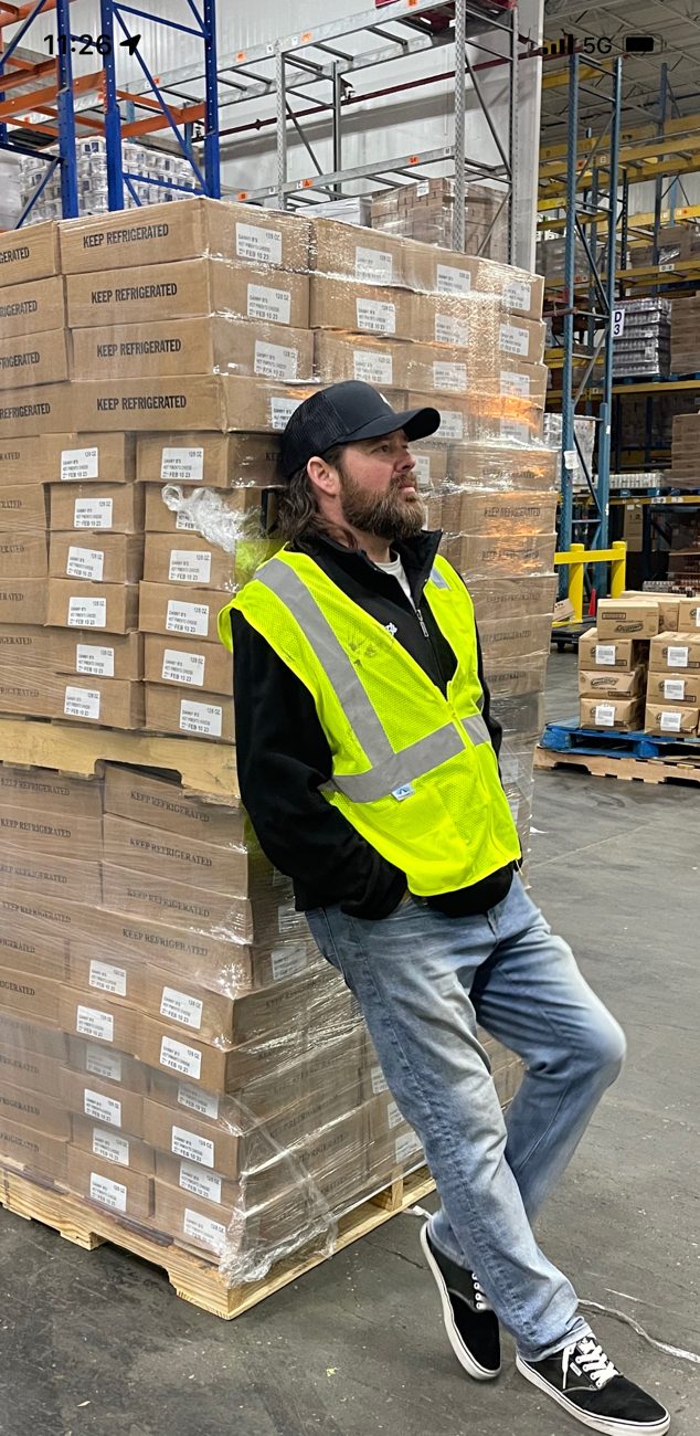 Danny B leaning against pallets of pimento cheese